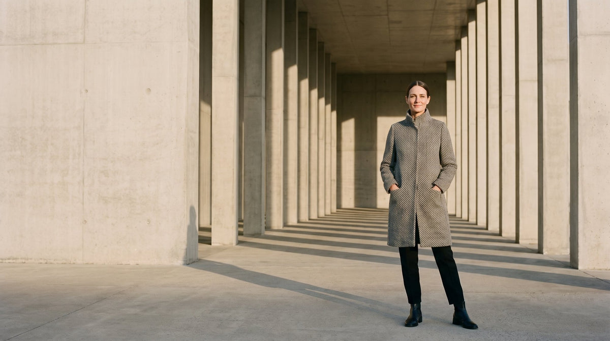Woman in a herringbone wool coat in a concrete colonnade