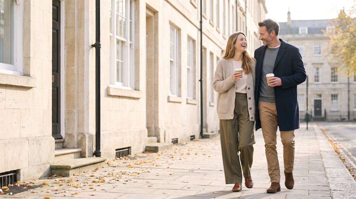 Couple walking with coffee on a city street in autumn knitwear and coats