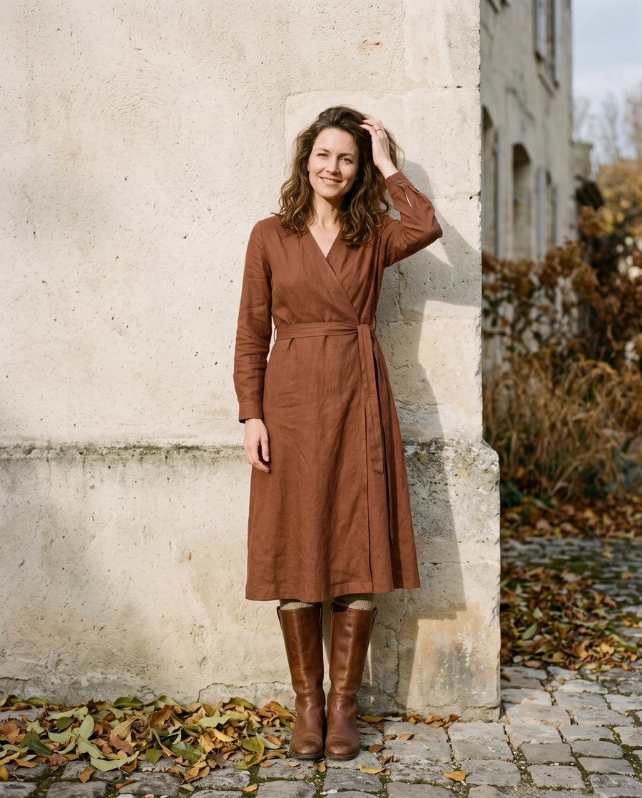 Woman in a rust wrap midi dress against a stone wall
